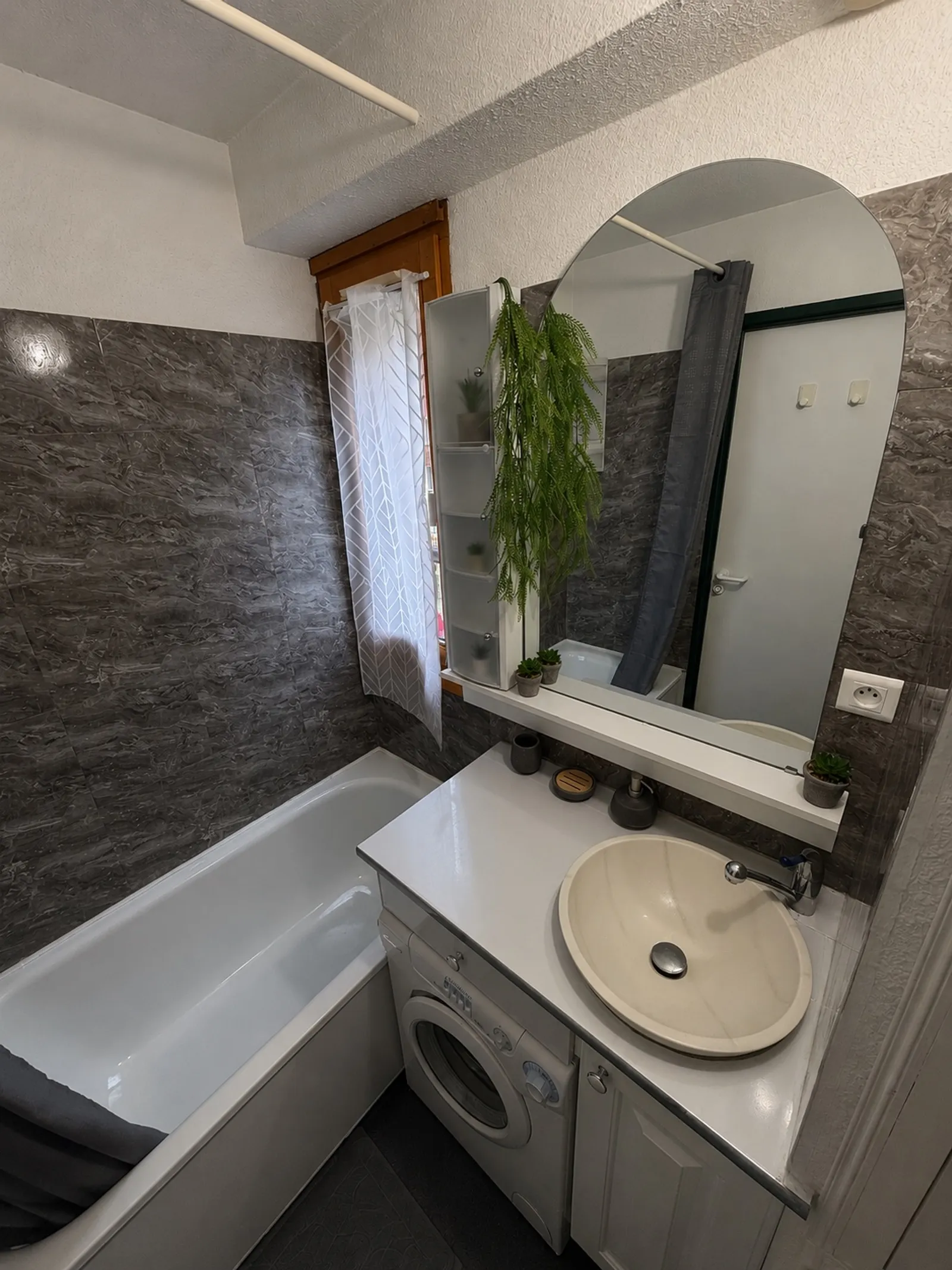 La salle de bain avec baignoire et lave-linge